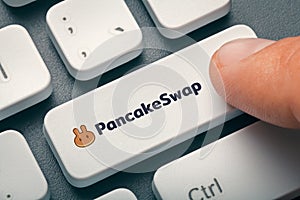 Index finger pressing computer key with pancakeswap altcoin logo photo