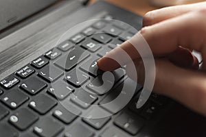 Index finger pressing enter button on a black laptop.