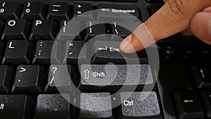 Index finger pressing enter button on keyboard