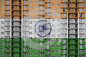 India flag depicted in paint colors on multi-storey residental building under construction. Textured banner on brick wall