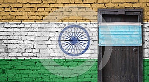 India flag painted on brick wall and closed door with medical mask protected