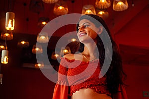 India girl long hair in red blouse stang lighting diyas in dark room photo