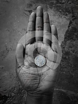 An Indian 20 paise coin in hand with black and white effect. Old indian currency stock photo.