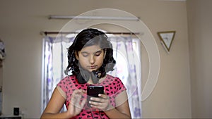 Indian aisan caucasian girl busy on phone checking text headphone in neck. Portrait of music lover front view.