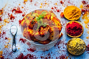 Indian appetizer dish i.e.Teekha Laal Batata or Spicy potato with all its ingredients and spices on a sliver wooden surface.This d