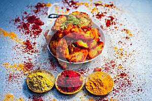 Indian appetizer dish i.e.Teekha Laal Batata or Spicy potato with all its ingredients and spices on a sliver wooden surface.This d