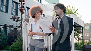 Indian Arabian male man businessman holding papers documents corporate discuss result plans with African American woman