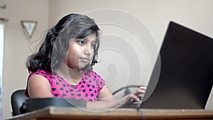 Indian asian caucasian girl with short hairs working typing on laptop at home office indoor. Close up side view shot.