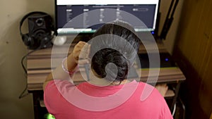 Indian asian caucasian woman in pink t-shirt working on desktop pc hand on chin. House wife browsing reading internet website blog