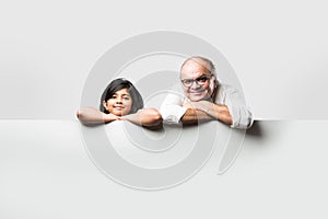 Indian asian cute little girl pointing at blank white board with grandpa or grandfather