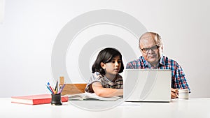 Indian asian Grandfather is teaching his granddaughter or grandaughter at home