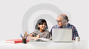 Indian asian Grandfather is teaching his granddaughter or grandaughter at home