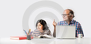 Indian asian Grandfather is teaching his granddaughter or grandaughter at home