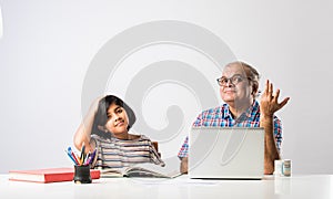 Indian asian Grandfather is teaching his granddaughter or grandaughter at home