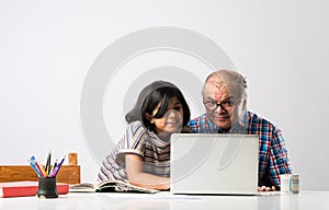 Indian asian Grandfather is teaching his granddaughter or grandaughter at home