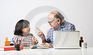 Indian asian Grandfather is teaching his granddaughter or grandaughter at home