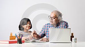 Indian asian Grandfather is teaching his granddaughter or grandaughter at home