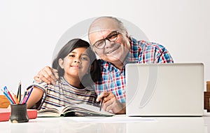 Indian asian Grandfather is teaching his granddaughter or grandaughter at home