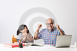 Indian asian Grandfather is teaching his granddaughter or grandaughter at home