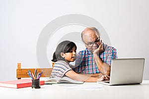 Indian asian Grandfather is teaching his granddaughter or grandaughter at home