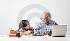 Indian asian Grandfather is teaching his granddaughter or grandaughter at home