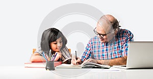 Indian asian Grandfather is teaching his granddaughter or grandaughter at home