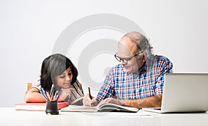 Indian asian Grandfather is teaching his granddaughter or grandaughter at home