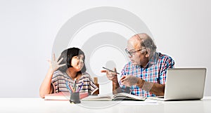 Indian asian Grandfather is teaching his granddaughter or grandaughter at home