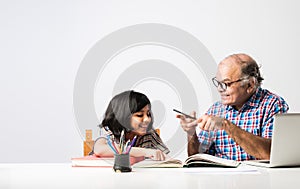 Indian asian Grandfather is teaching his granddaughter or grandaughter at home