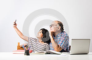 Indian asian Grandfather is teaching his granddaughter or grandaughter at home