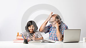 Indian asian Grandfather is teaching his granddaughter or grandaughter at home