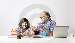 Indian asian Grandfather is teaching his granddaughter or grandaughter at home