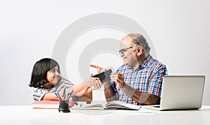 Indian asian Grandfather is teaching his granddaughter or grandaughter at home