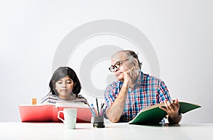 Indian asian Grandfather is teaching his granddaughter or grandaughter at home