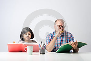 Indian asian Grandfather is teaching his granddaughter or grandaughter at home