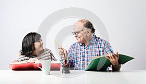 Indian asian Grandfather is teaching his granddaughter or grandaughter at home