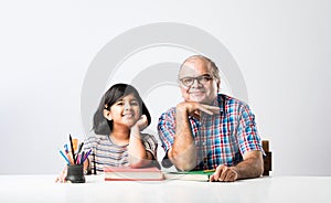 Indian asian Grandfather is teaching his granddaughter or grandaughter at home