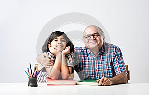 Indian asian Grandfather is teaching his granddaughter or grandaughter at home