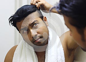 Indian asian man looking after his appearance in front of a mirror beauty styling lifestyle.hair styling