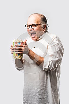 Indian Asian old man eating popcorn from Box or container