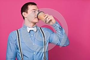 Indian/asian young man holding paper coffee cup with a black plastic cap isolated on a white background in the studio, advertising