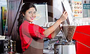 Indian barista filling coffee grinder