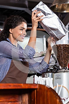 Indian barista filling coffee grinder