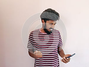 Indian beard man looking at his mobile phone and giving reaction