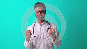 indian bearded cardiologist man with eyes glasses in white medical coat with stethoscope in blue studio background