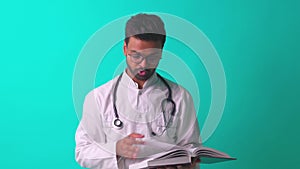 indian bearded cardiologist man with eyes glasses in white medical coat with stethoscope in blue studio background