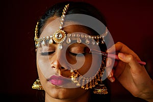 Indian beautiful female in golden rich jewelery and tradition saree face closeup professional make-up wearing bindi on photo