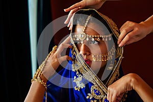 Indian beautiful female in golden rich jewelery and tradition saree face closeup professional make-up wearing bindi on photo