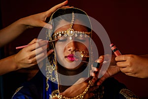 Indian beautiful female in golden rich jewelery and tradition saree face closeup professional make-up wearing bindi on photo