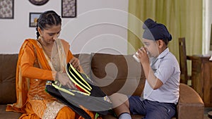 Indian beautiful mother happily packing her son`s backpack for school - Sikh family